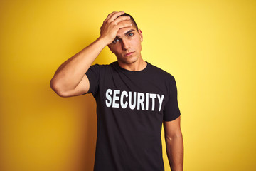 Young safeguard man with security t-shirt over yellow isolated background stressed with hand on...
