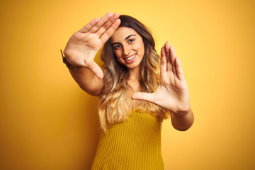 Young beautiful woman wearing t-shirt over yellow isolated background doing frame using hands palms and fingers, camera perspective - obrazy, fototapety, plakaty