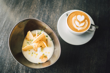 Delicious Vanilla dessert with cup of coffee on dark table