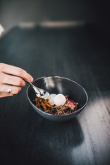 Chef making Miso Ramen Asian noodles with egg, enoki and pak choi cabbage in bowl on dark wooden background background