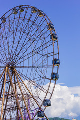 Ferris wheel in sunny summer Sochi on blue cloudy sky background