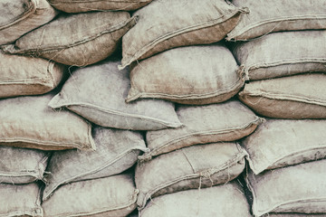 Background of lying on top of each other gray sandbags. Bags to strengthen the defensive structure during the battle. Sand bag flood protection wall texture, texture.