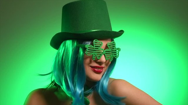 St. Patrick's Day leprechaun model girl in green hat and costume over green background, Dancing on party, Smiling. Patrick Day pub party, celebrating. Green beer. Ads. 4K UHD slow motion