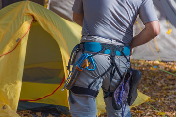Close-up of a thigh climber with equipment on a belt and near the tents going to climb