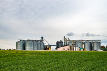 Fototapeta na wymiar agro-processing and manufacturing plant for processing and silver silos for drying cleaning and storage of agricultural products, flour, cereals and grain. Granary elevator