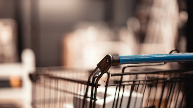 Supermarket aisle with shopping cart in blurred department store background.