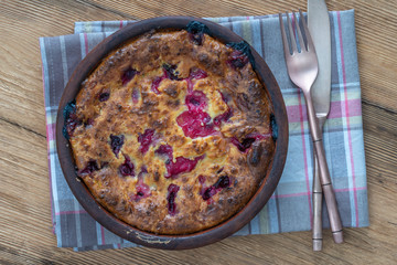 Sweet cottage cheese casserole with gooseberry and semolina on wooden table. Ceramic bowl with baked cottage cheese casserole