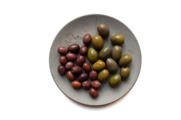 Black and green olives on grey plate isolated on white background from a high angle view