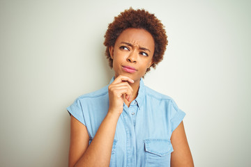 Fototapeta na wymiar Young beautiful african american woman with afro hair over isolated background with hand on chin thinking about question, pensive expression. Smiling with thoughtful face. Doubt concept.