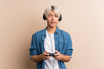 Young asian man over isolated background playing at videogames