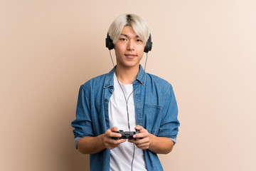 Young asian man over isolated background playing at videogames