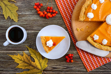 Piece of traditional homemade pumpkin pie and a cup of coffee on a wooden table. Healthy food, dessert for gourmets. Thanksgiving theme. Traditional autumn baking. Top view.