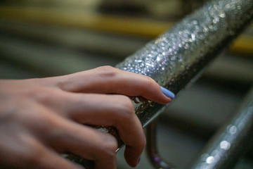 Close up of a girl's hands on an iron railing with raindrops in the evening