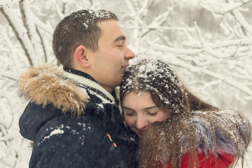The guy and the girl have a rest in the winter woods. Husband and wife in the snow. Young couple walking in winter park	
