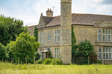 Grand exterior view of a Grade II listed Tudor Mansion in early summer. Showing part of the unusual turret which extends above the roofline.