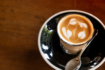 Hot latte in a clear glass on a wooden table