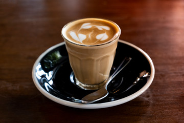 Hot latte in a clear glass on a wooden table