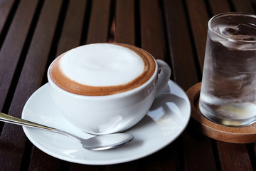 Hot cappuccino with cold water on a wooden table