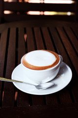 Hot cappuccino with cold water on a wooden table