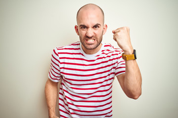 Young bald man with beard wearing casual striped red t-shirt over white isolated background angry...