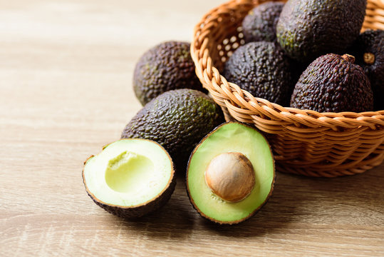 Ripe hass avocado fruit in basket on wooden background