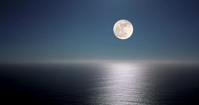 Full moon glow over the ocean illuminated reflection over the ripples with clear blue night sky