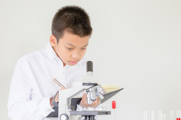 Children science concept, Portrait of Kid boy using microscope in science lesson at the laboratory and recording the results