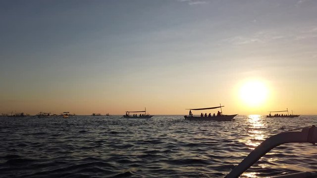 many Indonesian fishing boats are jukung, at dawn.  tourists sit in boats and take pictures. very beautiful dawn.