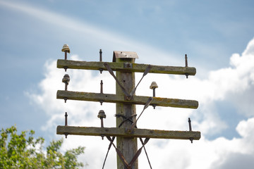 Isolated image of a very old and abandoned rail side power cable wooden pole. Showing eroded electrical insulators, the gantry have long been used.