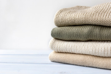 Pile of knitted cashmere sweaters on light blue wooden background. Folded autumn and winter...
