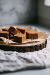 Fresh caramel fudge candies on a wooden plate with copy space in marble background