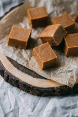 Fresh caramel fudge candies on a wooden plate with copy space in marble background