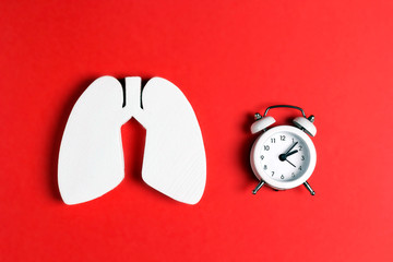 Prevention of pulmonary disease. Lung symbol and alarm clock on a red background.