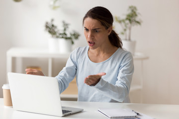 Angry millennial female worker employee irritated by slow computer work.