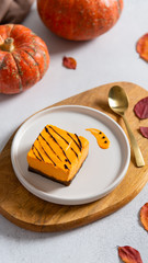 Pumpkin orange cheesecake with chocolate for Thanksgiving. Pumpkins and autumn leaves on the background. Autumn dessert. Healthy food