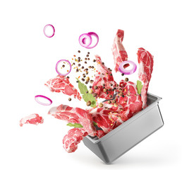 Cooking concept. Pieces of raw meat fly out of the capacity isolated on a white background. Splash.