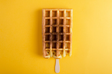 Closeup of waffle on the stick.Sweet dessert on the yellow background