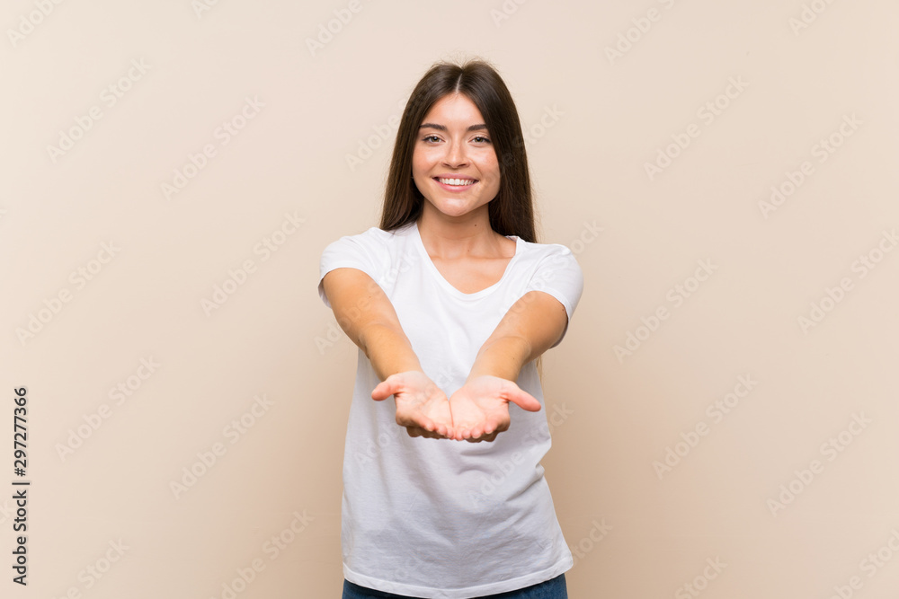 Wall mural Pretty young girl over isolated background holding copyspace imaginary on the palm to insert an ad