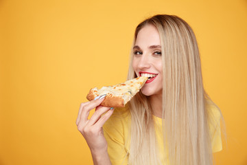 Happy woman eating tasty pizza for lunch in the yellow studio