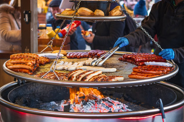 Grilling sausages on barbecue grill at Christmas market winter wonderland in London
