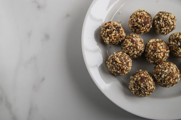 Energy balls with copy space. Homemade healthy dessert cooked with dates, nuts, dry fruits and cocoa. Organic dry fruits snacks on marble background