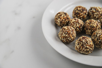 Energy balls with copy space. Homemade healthy dessert cooked with dates, nuts, dry fruits and cocoa. Organic dry fruits snacks on marble background