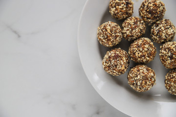 Energy balls with copy space. Homemade healthy dessert cooked with dates, nuts, dry fruits and cocoa. Organic dry fruits snacks on marble background