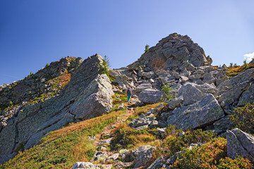 A hiker walking on the mountain path on a sunny autumn day.
