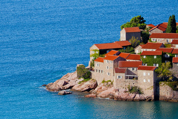 Fototapeta na wymiar houses covered with red tiles and bright blue sea close-up Montenegro, Sveti Stefan.