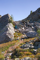 Fototapeta na wymiar A hiker walking on the mountain path on a sunny autumn day.