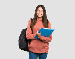 Young student woman holding notebooks keeping the arms crossed in frontal position over isolated grey background - obrazy, fototapety, plakaty
