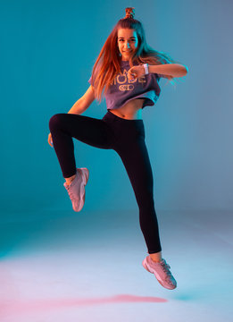 Young stylish girl dancing zumba in the Studio on a colored neon background. Dance poster design.