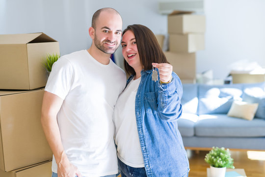 Young couple smiling very happy showing keys of new home, moving and buying new apartmet concept