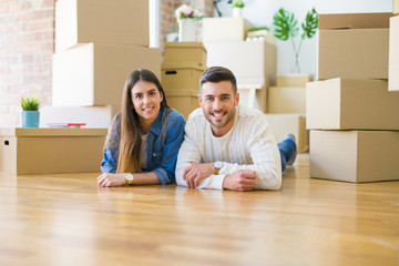 Young beautiful couple lying on the floor of new house, smiling in love very happy for moving to new apartment